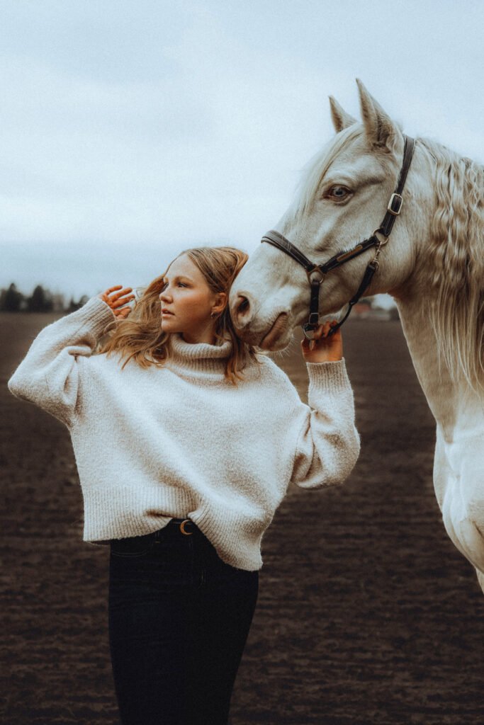 Eine Frau steht neben einem weißen Pferd.