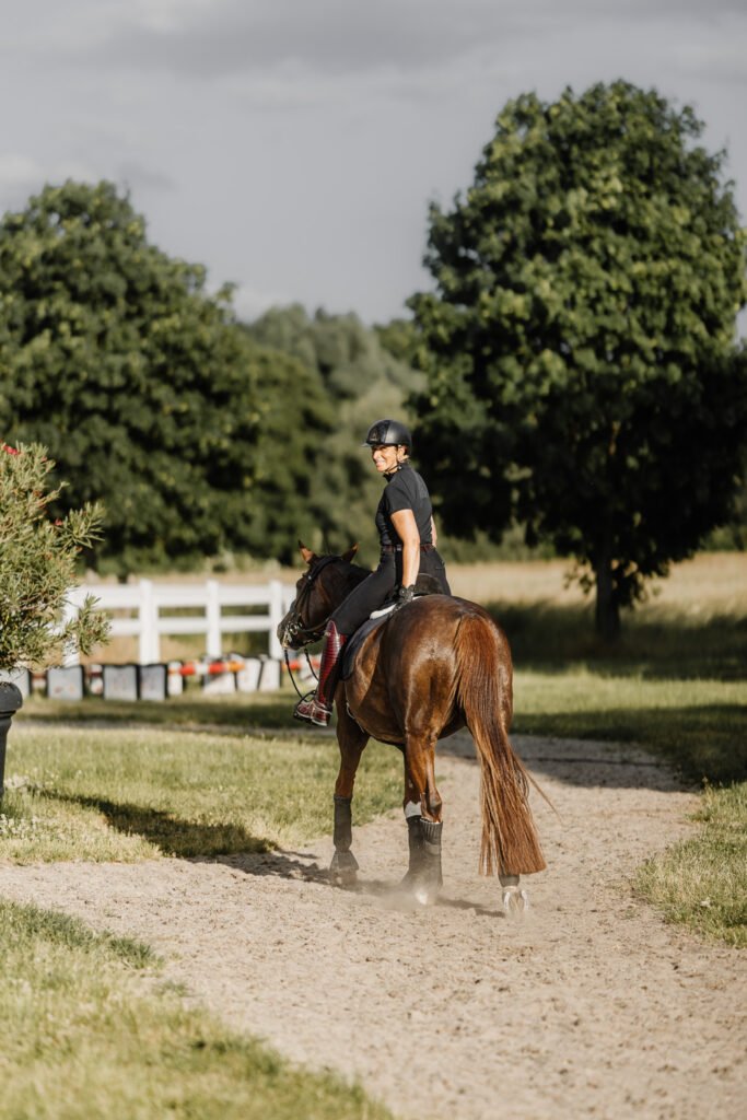Eine Frau reitet auf einem Feldweg.