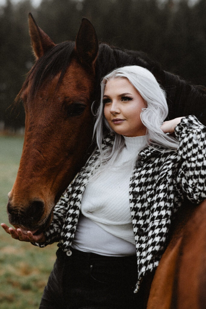 Eine Frau posiert mit einem Pferd auf einem Feld.