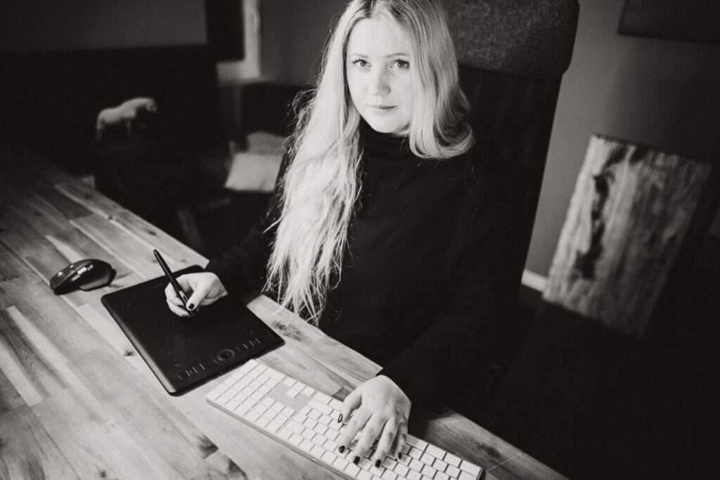 Ein Schwarz-Weiß-Foto einer Frau, die an einem Schreibtisch sitzt.