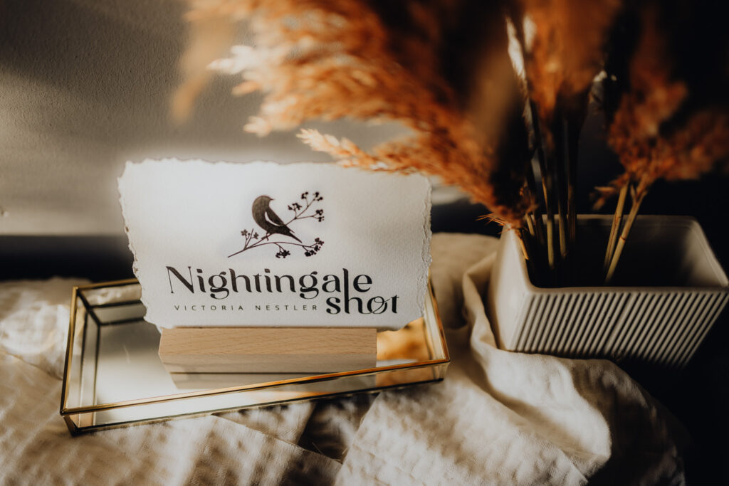 Logodesign "Nightingale Shot" auf einem Bett.